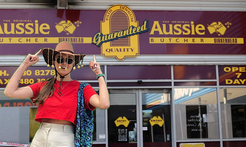 Author, wearing cork hat, points up at Aussie Butcher sign.