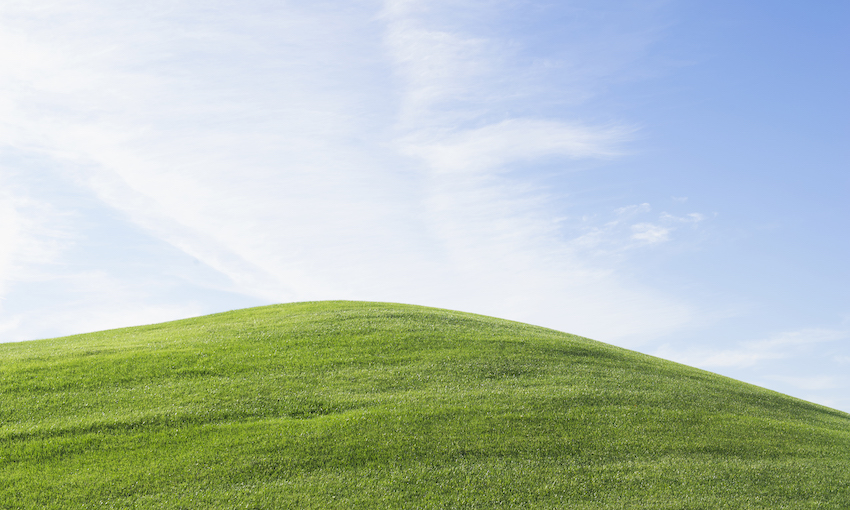 Rolling green hill under blue sky
