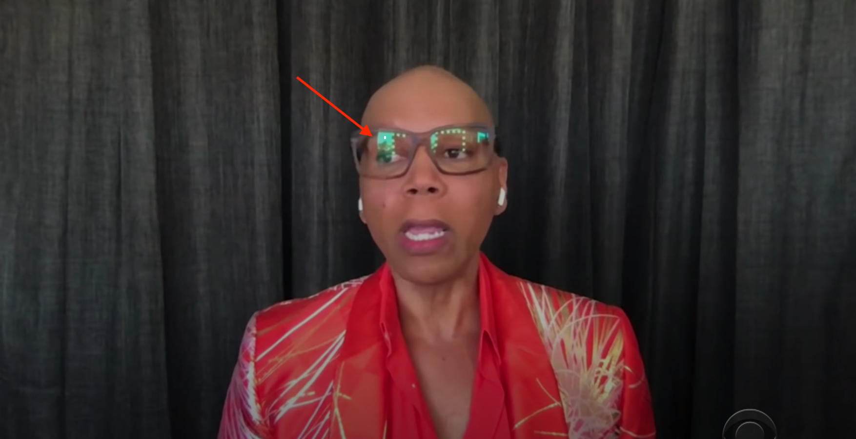 RuPaul in front of curtains with an arrow pointing to the reflection