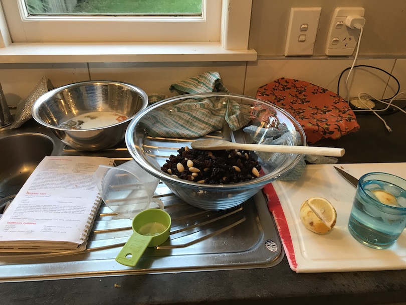 Bowls and measuring spoons, etc, on a bench. A drink and lemon to one side.