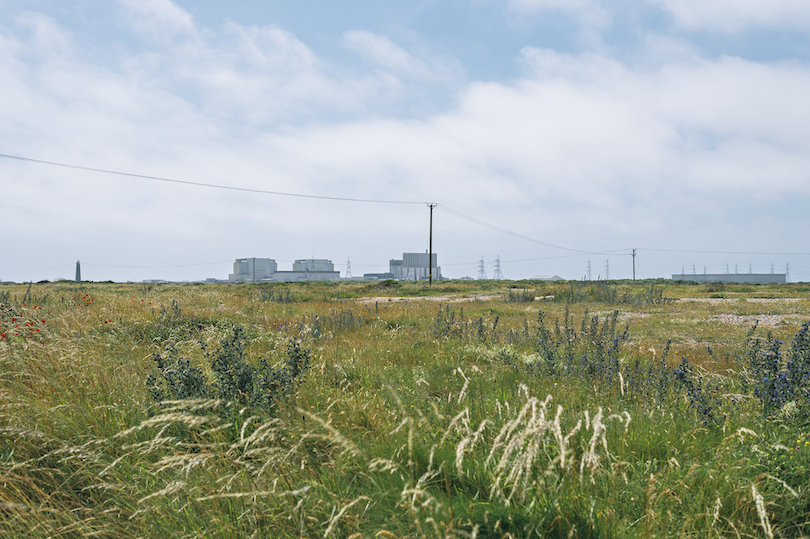 Photo of scrubby landscape, blue cloud-swept sky, looks cold. In the distance, a nuclear power plant.