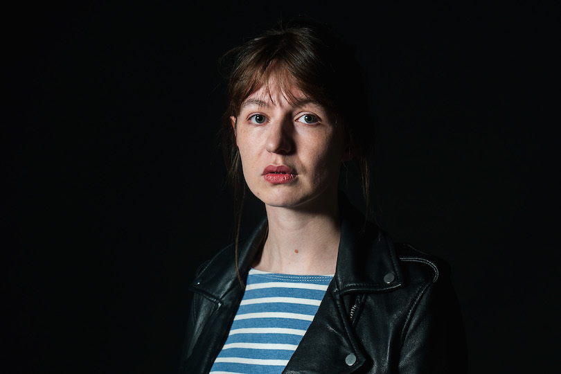 Photograph of a young woman, pale, serious-looking, partly in shadow