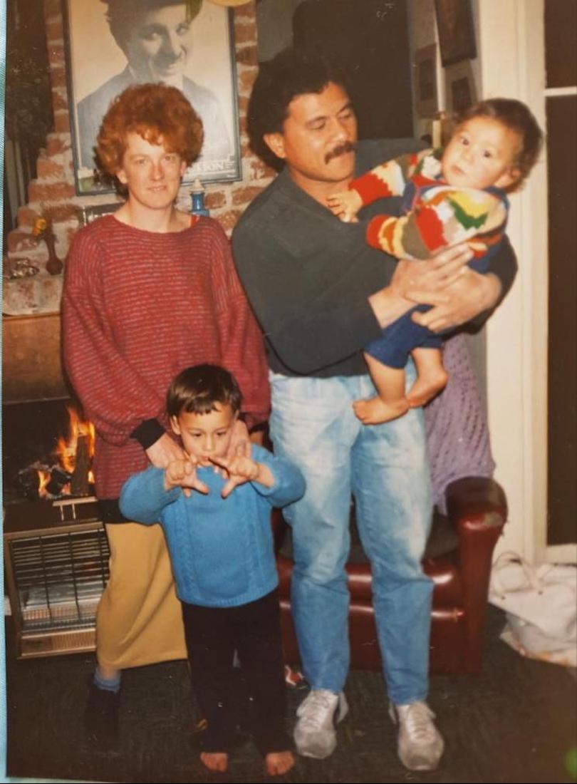Old family photo of a young couple with a preschooler and a baby, both looking like mischief. Taken in the 80s.