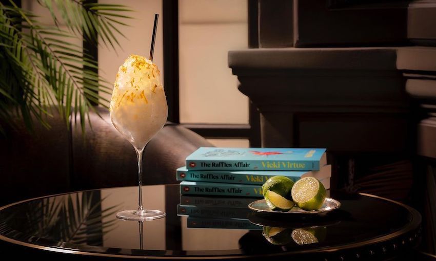 Photo d'un cocktail chic à côté d'une pile de livres et d'un plat de citrons verts coupés.  Tous de très bon goût et cher. 