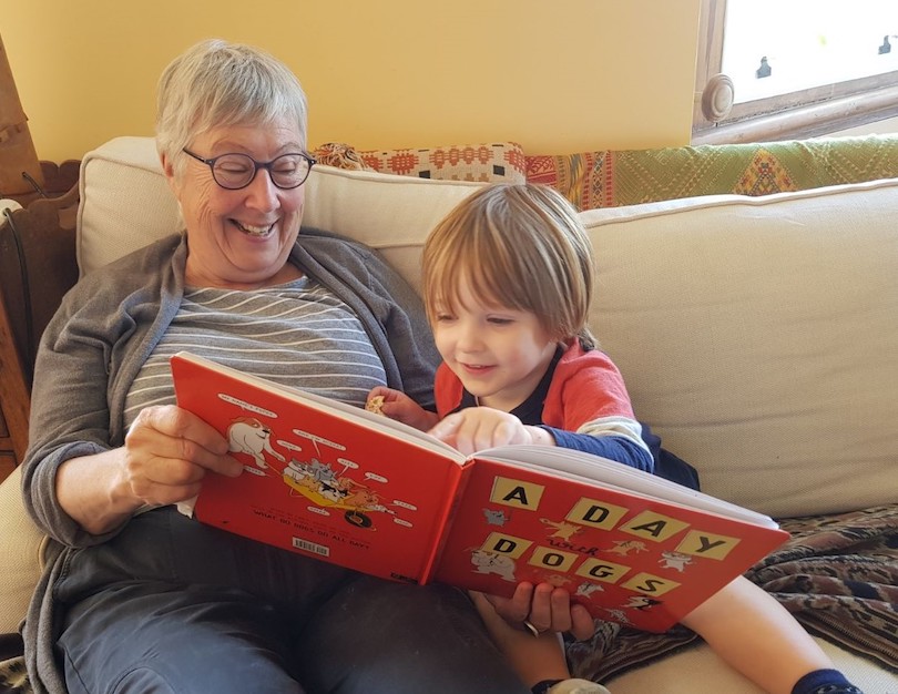 A grandmother and a young boy delight in a picture book.